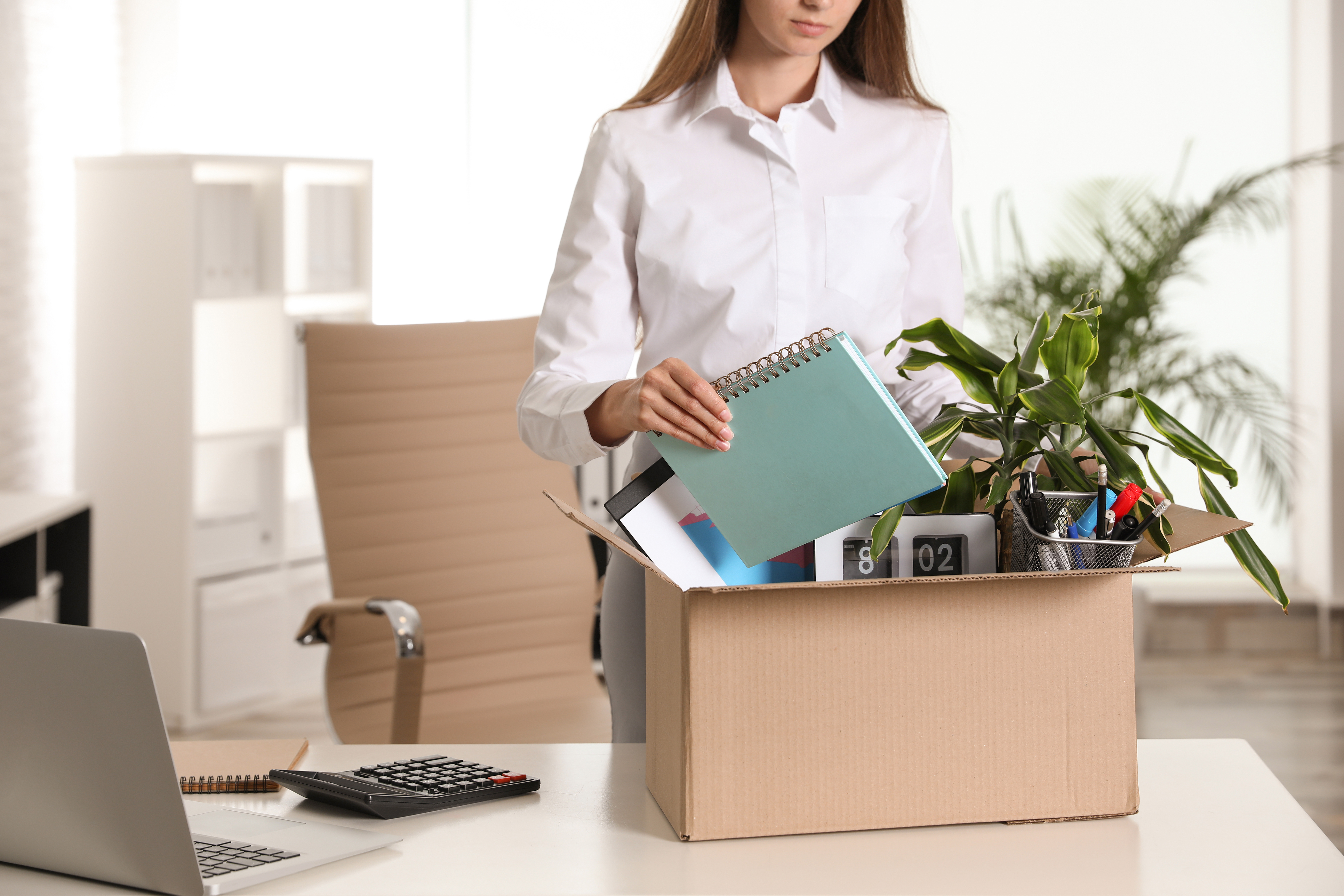 Upset young woman packing stuff in box office