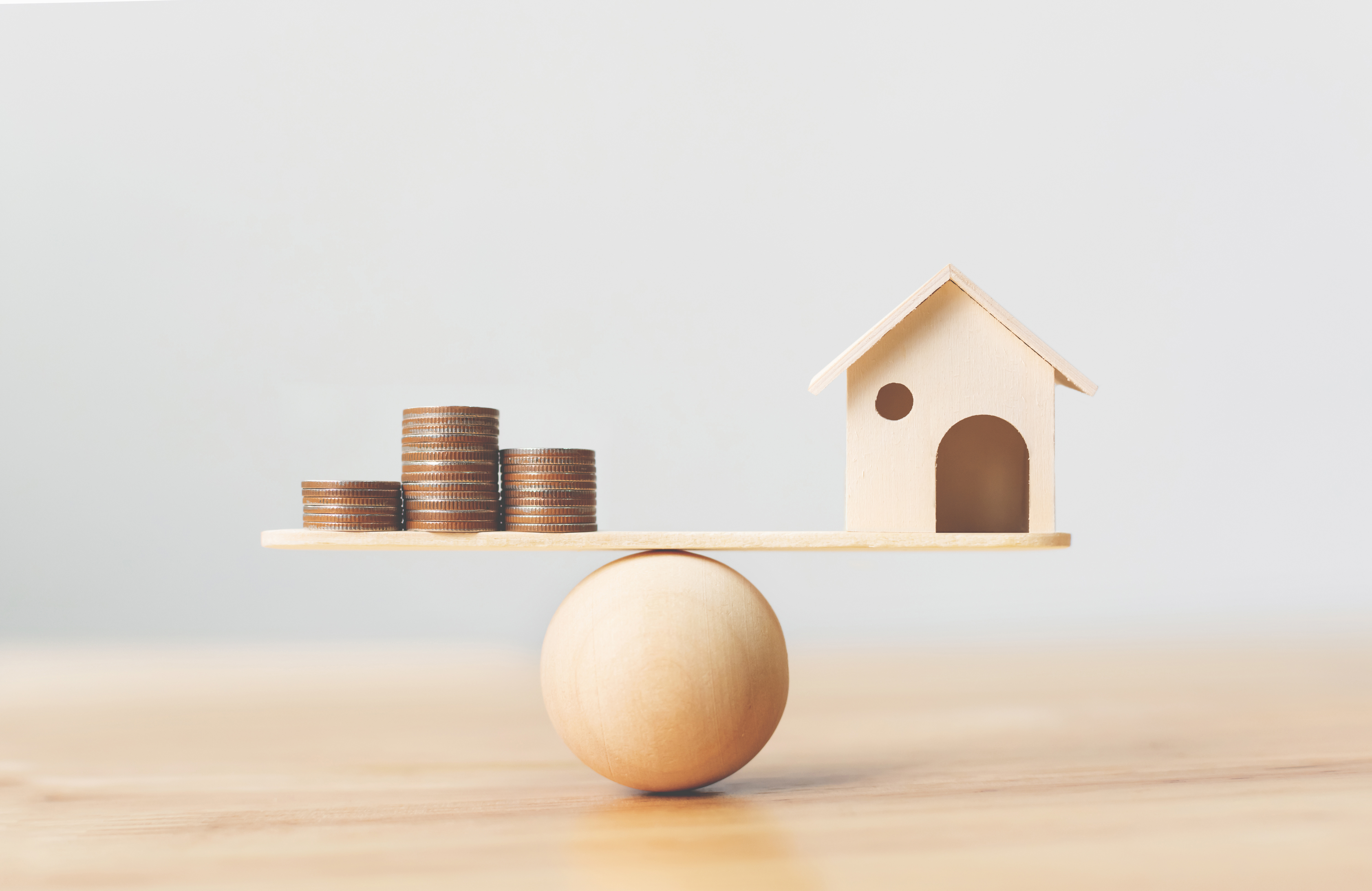 Wooden home and money coins stack on wood scale @Monster Ztudio