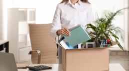 Upset young woman packing stuff in box office
