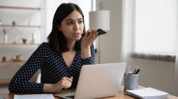 Une femme fait un appel téléphonique tout en consultant son ordinateur portable