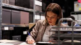 Jeune femme qui écrit à la main dans un dossier 